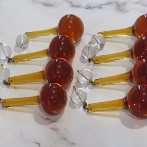 May include: Eight amber glass teardrop chandelier crystals with clear glass beads and gold-toned metal accents.