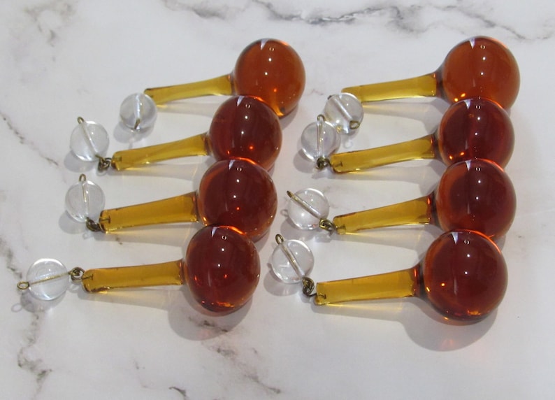 May include: Eight amber glass teardrop chandelier crystals with clear glass beads and gold-toned metal accents.