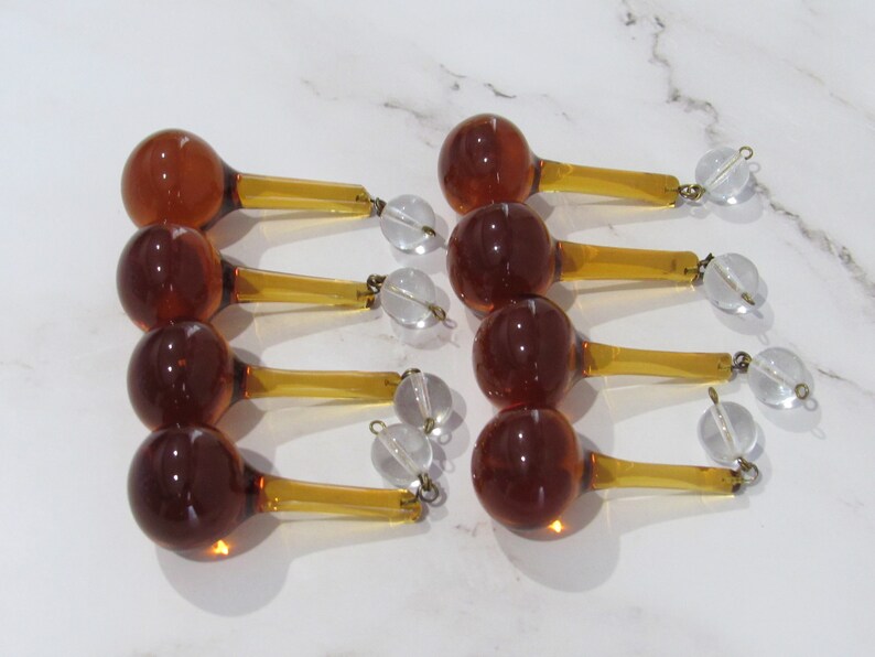 May include: Ten amber glass teardrop chandelier crystals with clear glass beads and gold metal accents.