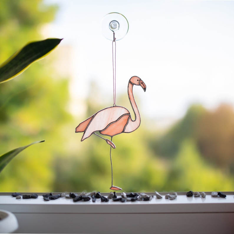 A stained glass suncatcher shaped like a flamingo on one leg