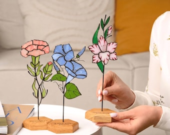 May include: Three stained glass flower sculptures featuring a pink carnation, blue morning glories, and a pink gladiolus. Each flower is mounted on a hexagonal wooden base with engraved text, including 'Grandma's Garden' and 'Love you, Mom'.