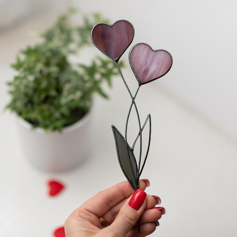 Stained glass suncatcher in a hand with 2 hearts instead of a pink and purple bud