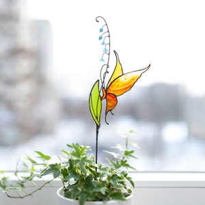 stained glass plant stake the orange butterfly that sits on the lily of the valley flower in a plant vase