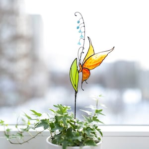 stained glass plant stake the orange butterfly that sits on the lily of the valley flower in a plant vase