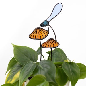 suncatcher in the form of two orange mushrooms with veins on which sits a dragonfly with blue wings