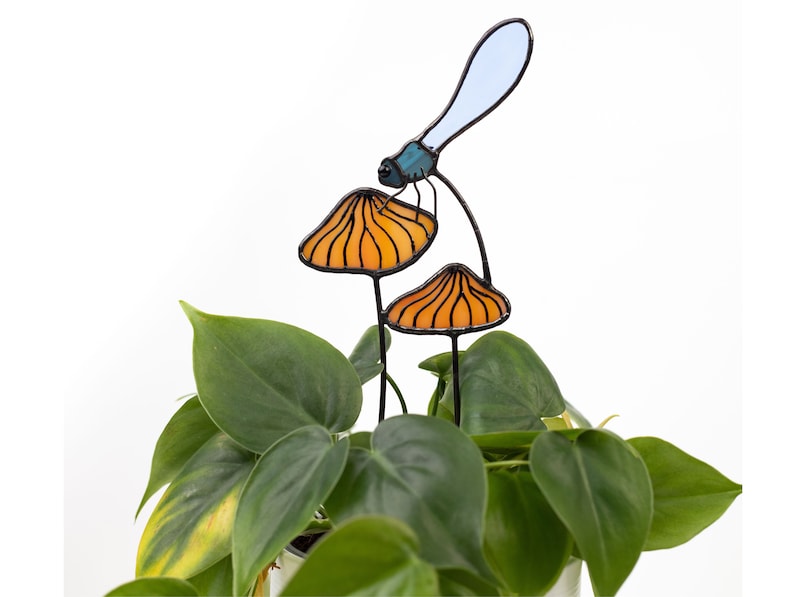 suncatcher in the form of two orange mushrooms with veins on which sits a dragonfly with blue wings