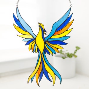 A stained glass suncatcher in the shape of a blue-yellow phoenix bird.