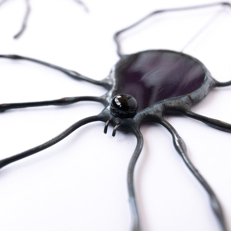 A stained glass suncatcher shaped like a spider