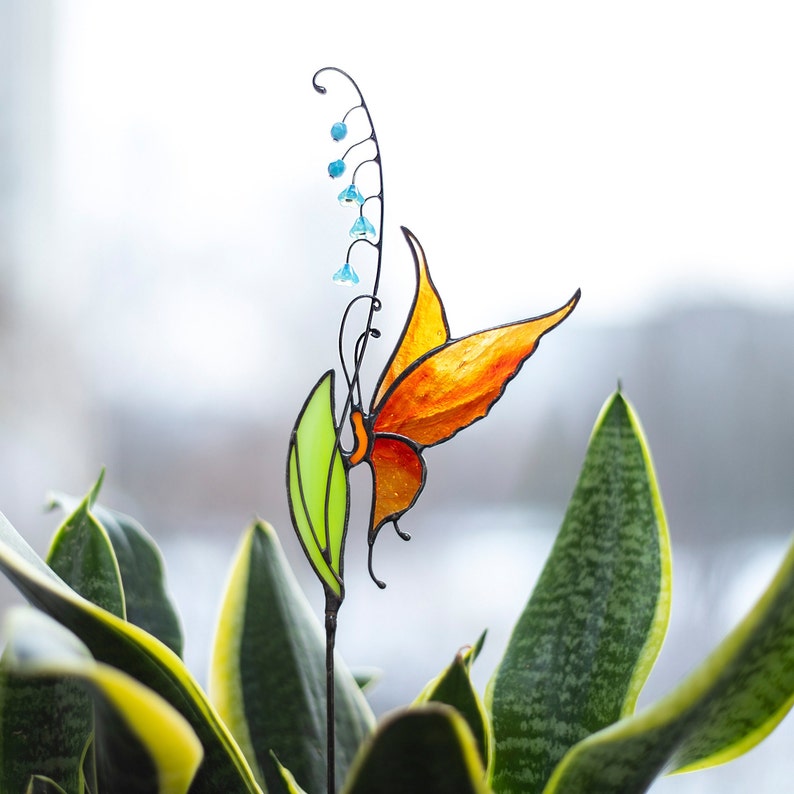 stained glass plant stake the orange butterfly that sits on the lily of the valley flower in a plant vase