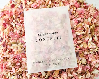 May include: A white paper bag filled with pink and cream flower petals. The bag has a black label that reads "throw some confetti" and "Isabella & Alexander 27.08.2025".