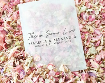 May include: A white paper bag with the text "Throw Some Love" in black cursive writing. Below the text is "Isabella & Alexander" and "Sunday 27th August 2023" in black print.