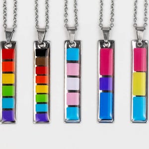 May include: Five silver necklaces with colorful rectangular pendants. Each pendant features a different color scheme, including rainbow, brown, pink, blue, and yellow.
