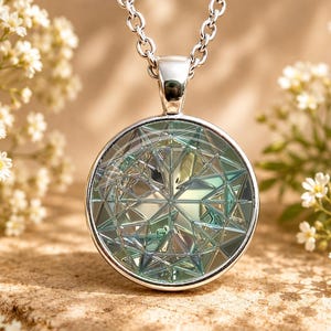 May include: A circular silver pendant necklace featuring a multifaceted, geometric glass insert with iridescent blue and green tones. The pendant is suspended from a silver chain, showcasing a complex, star-like pattern within the glass.