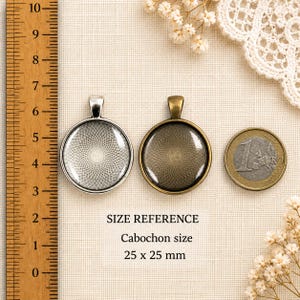 Puede incluir: Dos bandejas redondas de metal para colgantes con patrones geom&eacute;tricos, una plateada y otra bronce. Una regla de madera muestra un tama&ntilde;o de cabuj&oacute;n de 25 x 25 mm. Una moneda de un euro est&aacute; junto al colgante bronce como referencia.