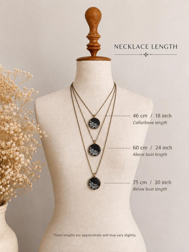 Puede incluir: Tres collares de tono bronce con colgantes redondos negros con patrones de encaje floral blanco. Las longitudes indicadas son 46 cm (clav&iacute;cula), 60 cm (sobre el busto) y 75 cm (bajo el busto) en un maniqu&iacute;.