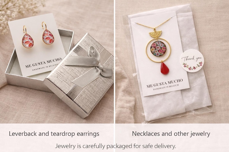 Puede incluir: Un par de pendientes de gota con cierre de palanca y estampado floral en tarjetas blancas marcadas ME GUSTA MUCHO, junto a un collar dorado con colgante floral circular y una pieza en forma de gota roja en una funda de pl&aacute;stico.
