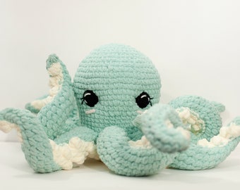 May include: A crocheted octopus plush toy with a light blue body and white accents. The octopus has large black eyes and a sweet expression.