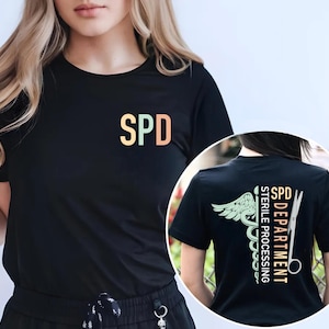 May include: Black t-shirt with the letters "SPD" in a gradient color scheme on the front. The back of the shirt features the text "SPD DEPARTMENT STERILE PROCESSING" with a medical symbol and scissors.