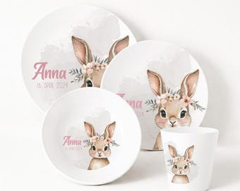 May include: A white ceramic children's dinnerware set featuring a watercolor illustration of a bunny wearing a floral crown. The set includes a plate, bowl, and cup, each with the name "Anna" and the date "16. April 2024" in pink script.