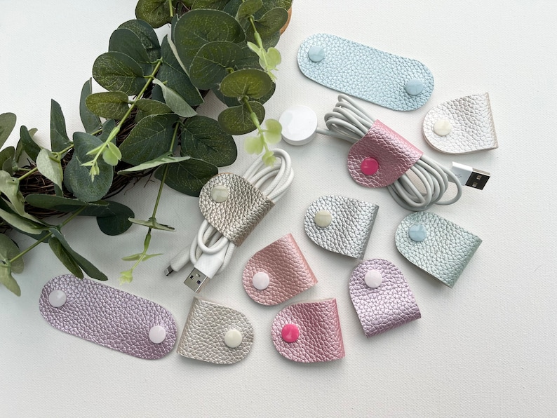 Peut inclure: Assortiment d'organisateurs de cordon en cuir de diff&eacute;rentes formes et tailles. Les organisateurs sont faits d'un mat&eacute;riau textur&eacute; et chatoyant et ont une fermeture &agrave; bouton.
