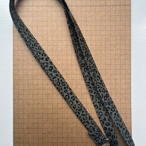 May include: A green lanyard with a black leopard print design and a silver metal clip.