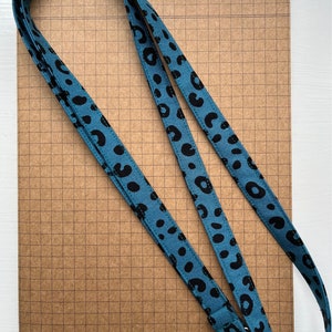 May include: A teal blue lanyard with a black leopard print pattern and a silver metal clip.