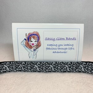 May include: Black and white skull patterned hair tie with a card that says "Sassy Glam Bands" and "Keeping you looking fabulous through life's adventures!"