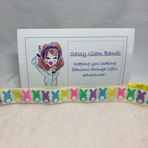 Puede incluir: Una diadema amarilla con fondo blanco y un patr&oacute;n repetido de siluetas de conejos de colores pastel. La diadema se muestra sobre una superficie blanca con una tarjeta que dice "Sassy Glam Bands! Keeping you looking fabulous through life's adventures!"
