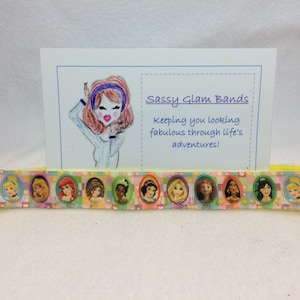Könnte beinhalten: Ein gelbes und weißes Band mit einem sich wiederholenden Muster von Prinzessinnen in ovalen Rahmen. Das Band trägt den Text "Sassy Glam Bands" und "Keeping you looking fabulous through life's adventures!" aufgedruckt.