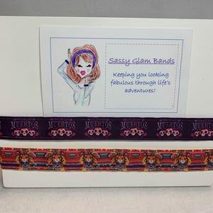 Texten "Dia de los Muertos" med sockerskallar nedanför på ett mycket djupt lila grosgrainband ELLER ett 2,5 cm brett pannband med La Catrina-tema och ränder