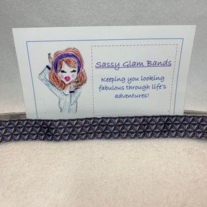 May include: A blue and gray patterned hair tie with a card that says "Sassy Glam Bands" and "Keeping you looking fabulous through life's adventures!"