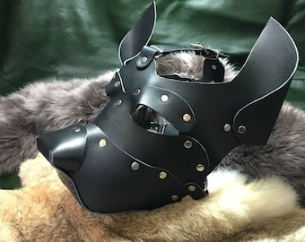 May include: Black leather dog mask with metal rivets and straps. The mask has a pointed snout and large ears.