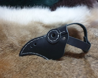May include: A black leather plague doctor mask with white stitching and a round eye hole. The mask is on a brown fur background.
