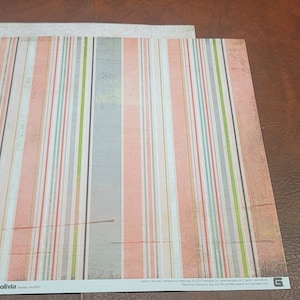 May include: Two sheets of patterned paper. One sheet has a white background with a subtle embossed pattern. The other sheet has a striped pattern with pink, gray, green, and blue stripes.