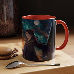 May include: A ceramic mug with a red interior and handle. The exterior features a detailed anime illustration of a character against a starry night sky with a full moon. The mug sits on a wooden surface.