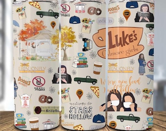 May include: A set of three stainless steel tumblers featuring a cream-colored background with various illustrations. The tumblers are decorated with images of a gazebo, books, coffee cups, pizza slices, and the text "Luke's Gilmore Girls".