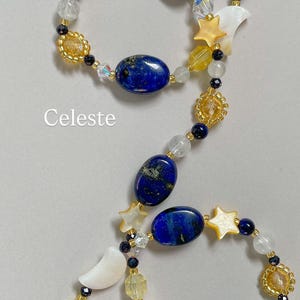 May include: A beaded necklace featuring oval lapis lazuli stones, white mother-of-pearl crescent moons, and star-shaped beads. The design includes yellow and clear faceted glass beads, small dark blue beads, and the word Celeste printed in white.