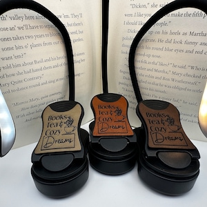 May include: Three black book lights with brown leather covers. Each cover has a different design with the text "Books Tea & Cozy Dreams".