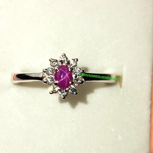 May include: A silver ring with a pink star ruby and a halo of small clear diamonds.