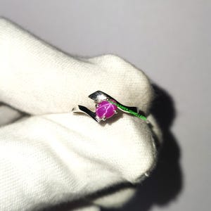 Peut inclure: Une bague en argent ornée d'une pierre précieuse rubis étoilé. La bague présente un design asymétrique moderne avec une finition polie. Le rubis étoilé est d'une couleur rose vif et constitue le point central de la bague.