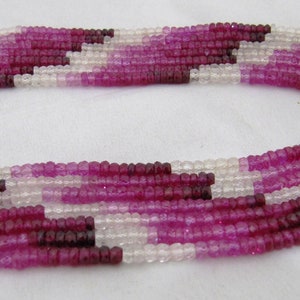 May include: A strand of pink, white, and red gemstone beads. The beads are faceted and have a slightly irregular shape. The strand is made up of multiple rows of beads.