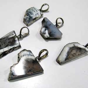 May include: Five silver pendants featuring white and grey dendritic agate stones. The stones are irregularly shaped and have a natural, rough texture. The pendants are attached to silver bail loops.