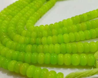 May include: A strand of bright green glass beads, each bead is slightly rounded and has a smooth, polished finish. The beads are strung on a thin cord and have a green tassel at the end.