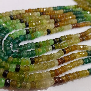 May include: A strand of green, brown, and yellow gemstone beads. The beads are faceted and have a slightly irregular shape. The strand is made up of multiple rows of beads.