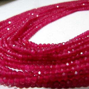 Può includere: Una collana di perline di pietra preziosa sfaccettata rosa. Le perline sono piccole e rotonde e sono infilate su un filo trasparente. Le perline sono disposte in un motivo sciolto e fluido.