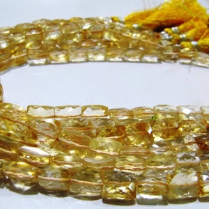 Puede incluir: Una hebra de cuentas de citrino amarillo dorado, cada cuenta es facetada y de forma rectangular. Las cuentas están enhebradas en un cordón fino y tienen un borla en cada extremo.