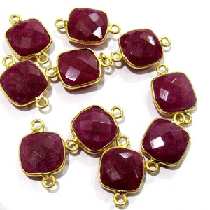 May include: Ten square-shaped gemstone beads with gold-toned metal connector loops. The beads are a deep burgundy red color.
