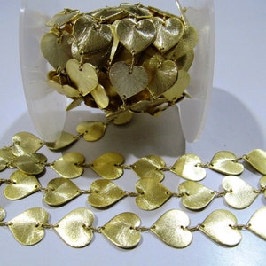 May include: A spool of gold-colored heart-shaped metal chain trim. The chain is made of small, interconnected hearts, and the hearts have a slightly textured surface.