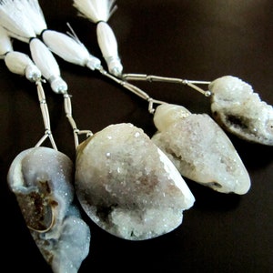 May include: Four white crystal pendants with silver chains and white feather tassels. The crystals are all different shapes and sizes.
