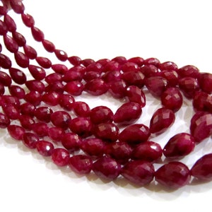 May include: A strand of deep red ruby gemstone beads in a faceted pear shape.